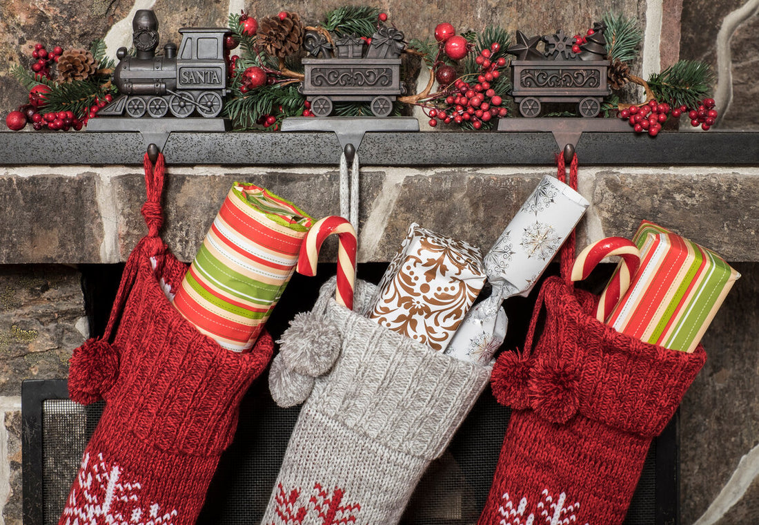 Three Christmas stockings with gifts in them hung on a fireplace
