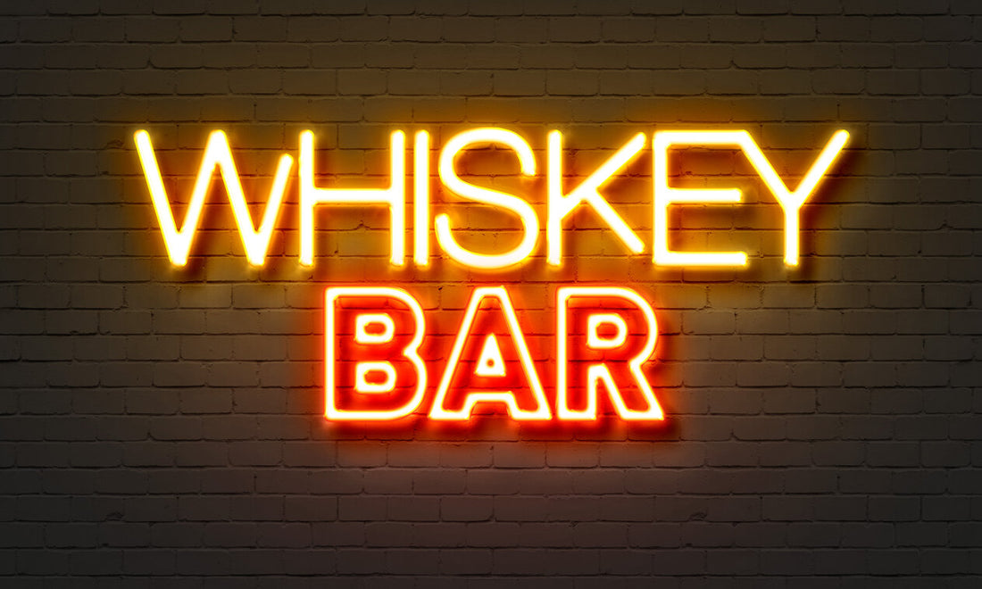 Neon bar sign with the words whiskey bar against a brick background